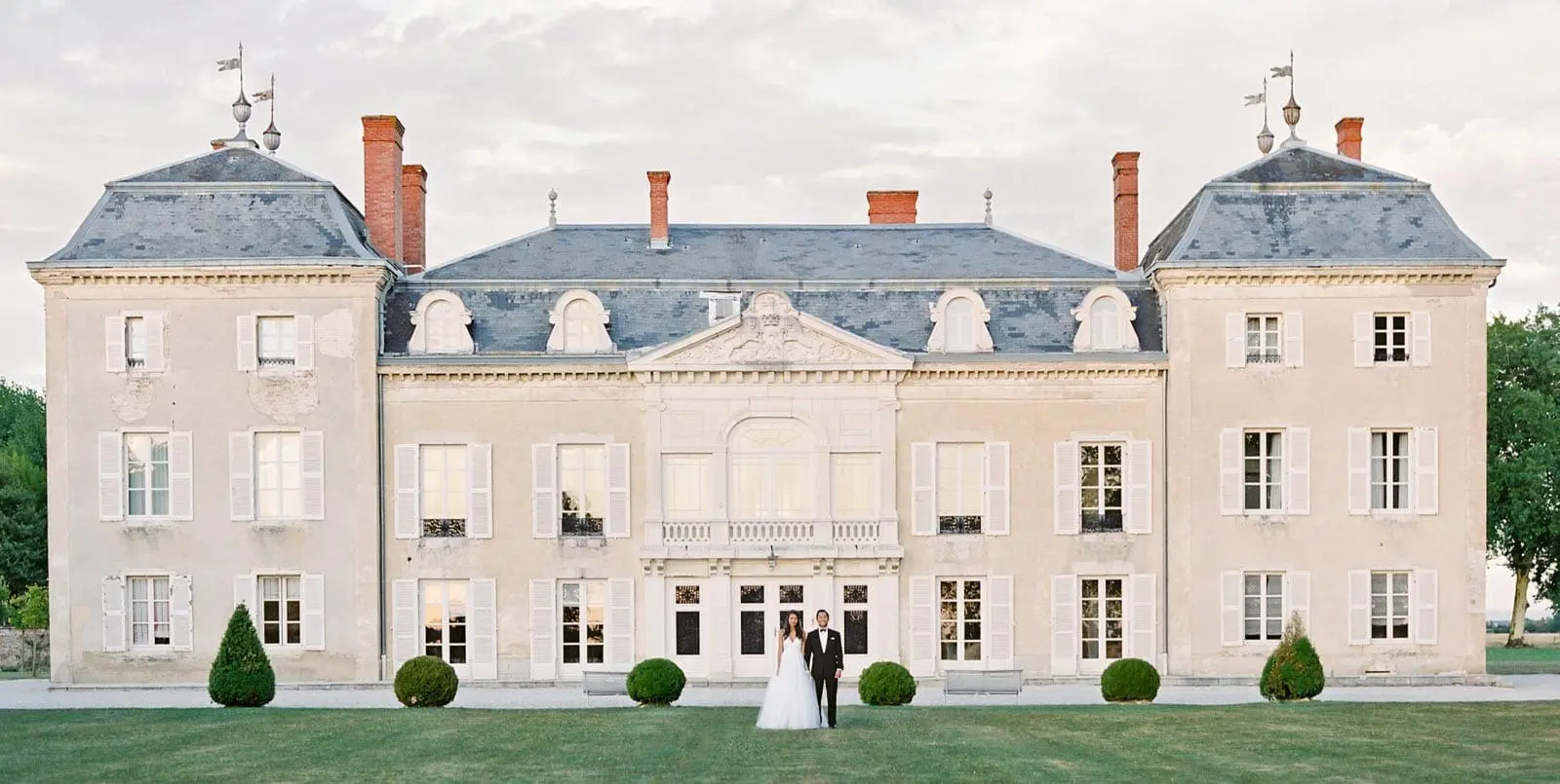 A beautiful home with a couple standing in front | Lisa Dupar Catering | Wedding & Event Catering in Seattle