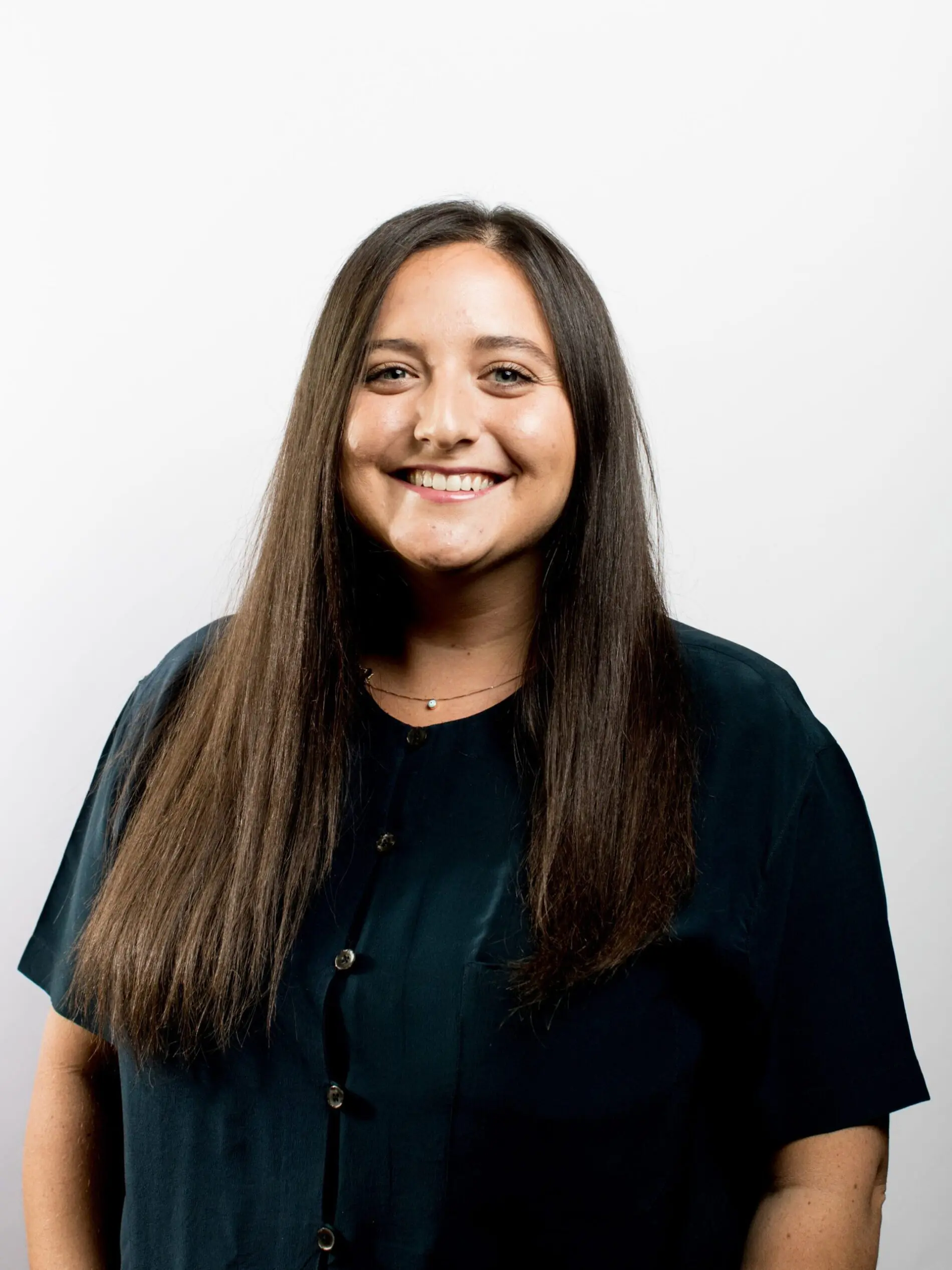 Seattle Catering A woman with long, straight hair and a dark button-up shirt smiling against a plain white background.