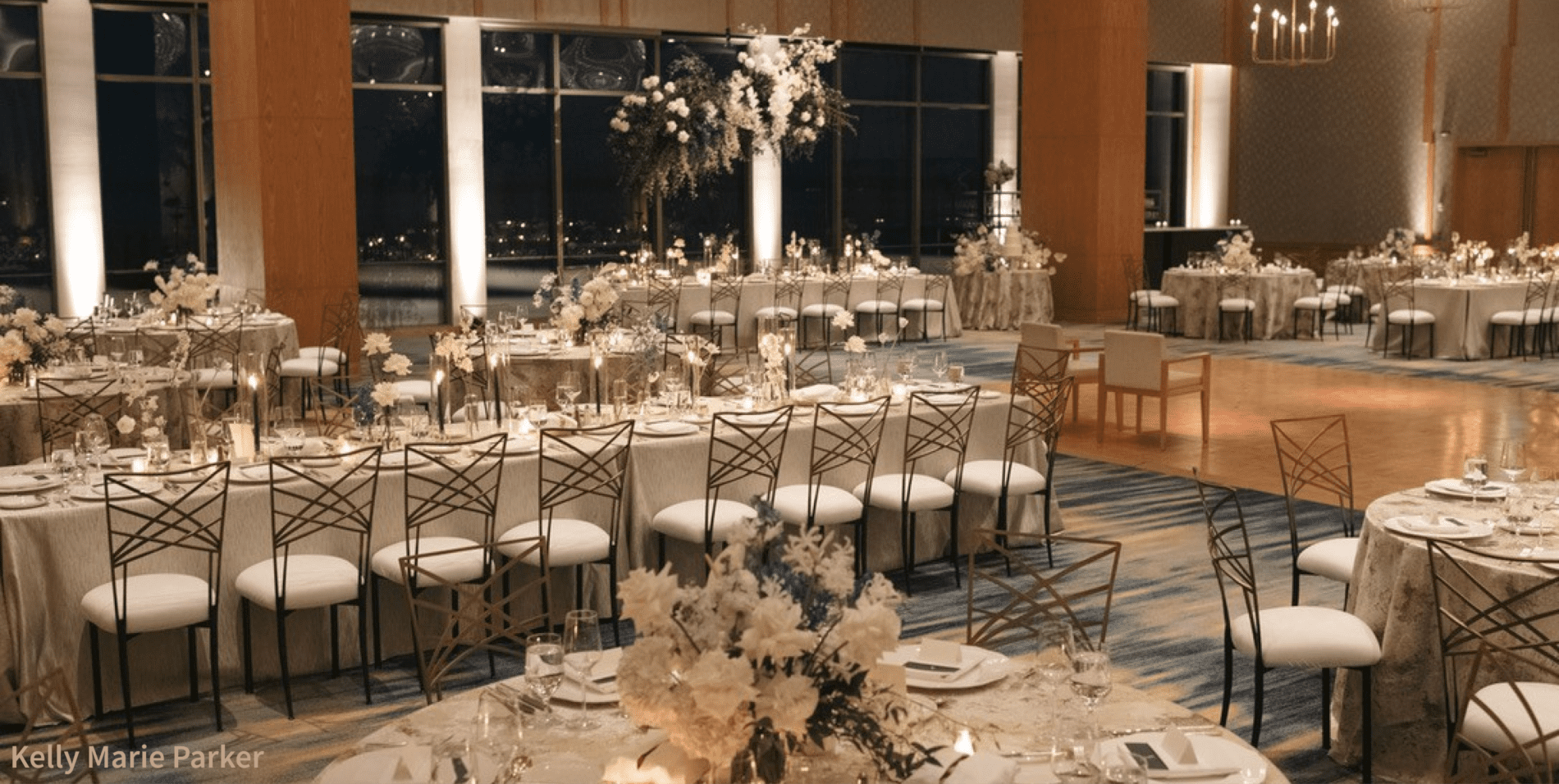 Seattle Catering A spacious banquet hall set for a formal event, featuring round and rectangular tables with elegant floral centerpieces, and a candlelit atmosphere, brought to life by the best event vendors in Seattle.