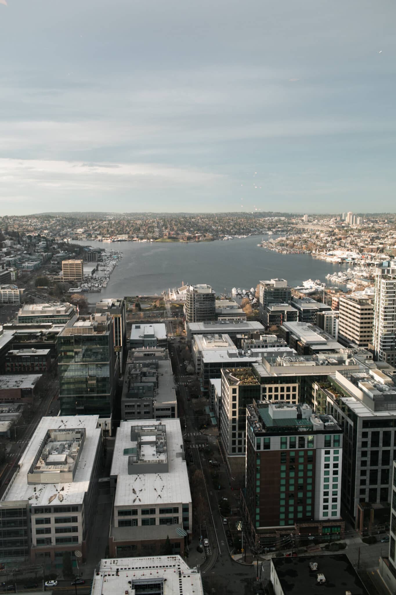 Aerial view of an urban cityscape featuring modern buildings, with a body of water surrounded by residential areas in the background—an ideal setting for wedding and event catering under a dramatic, cloudy sky.
