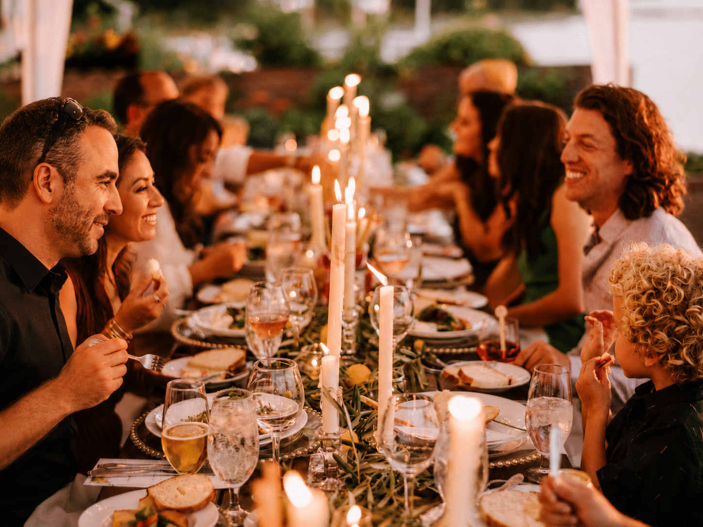 Guests smiling and connecting around a candlelit catered dinner table.
