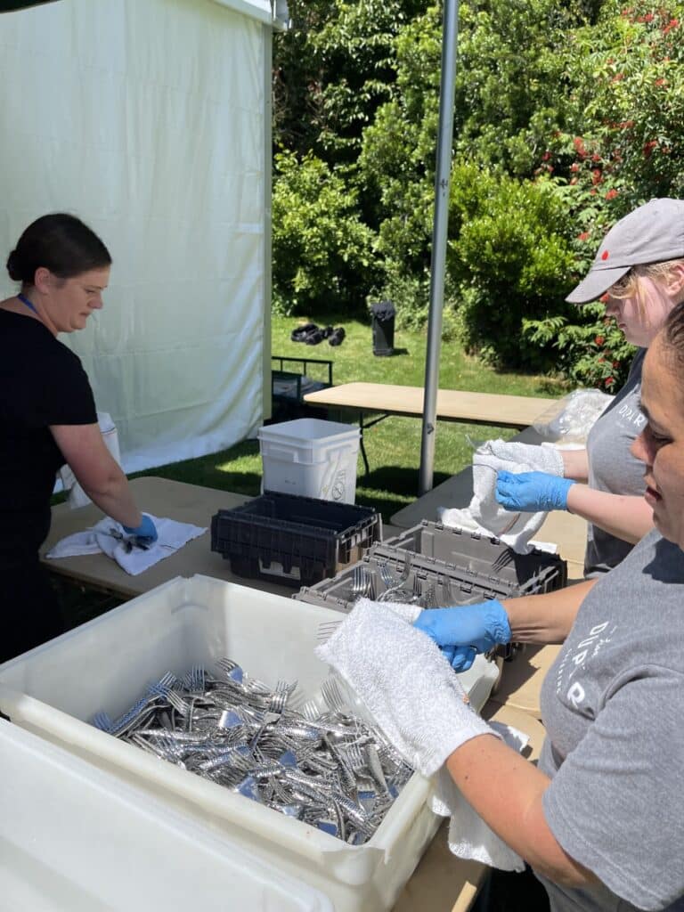 Lisa Dupar Catering team preparing flatware behind the scenes at an outdoor catered event