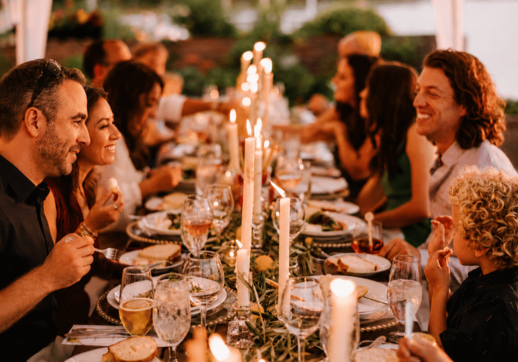 Guests smiling and connecting around a candlelit catered dinner table.